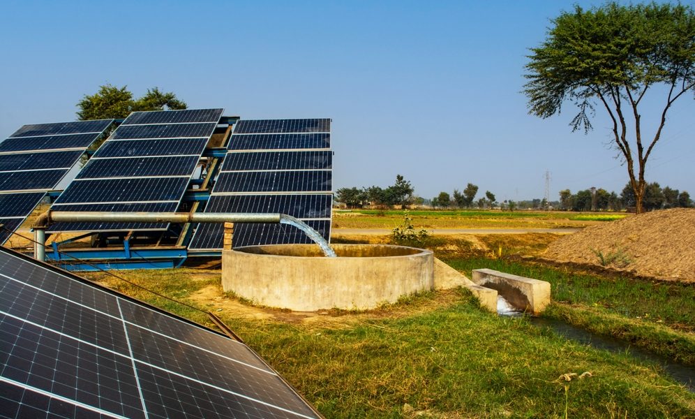 Système d’irrigation solaiare dans une ferme, avec des panneaux solaires alimentant une pompe qui extrait de l’eau d’un puits pour l’irrigation des cultures.